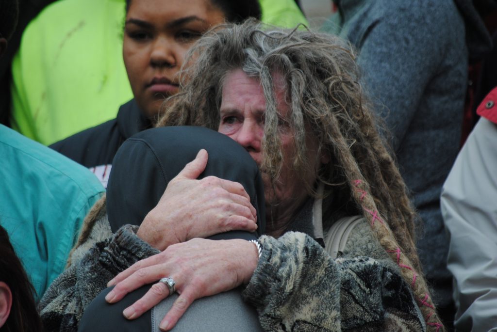 Sharon Irwin, the grandmother of Tony Robinson, Jr, comforts Tony's younger brother as attorneys recount the circumstances of his death at a recent press conference.
