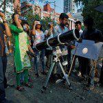 People look at planet Mercury transiting across the sun with solar filters at a public viewing in Kolkata