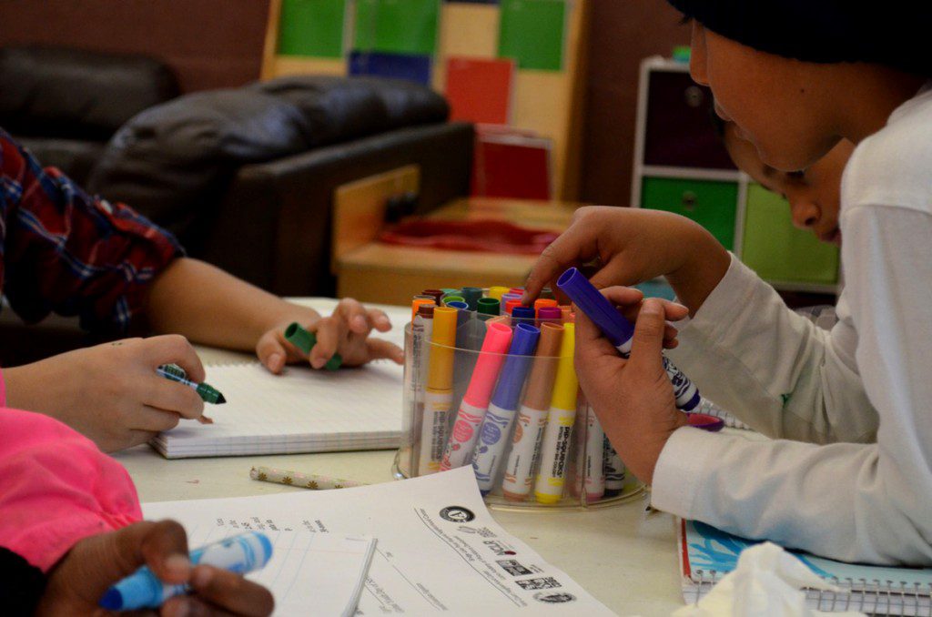 Vera Court students crowd a coloring table during after school programming. (Photo by Meagan Doll)